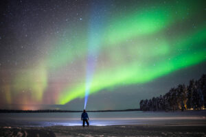 Person unter den Nordlichtern, Winterreise Finnland, Ruka, Lappland