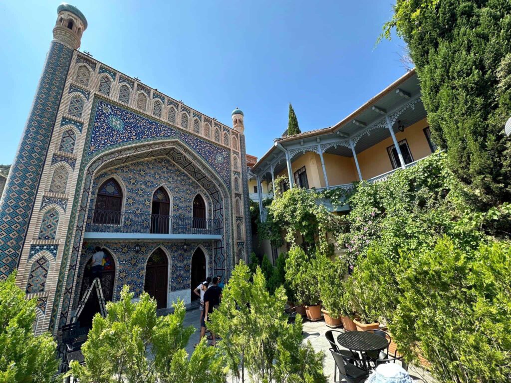 Bild zeigt ein orientalisches Haus vor blauem Himme. Es ist mit Mosaiken verziert